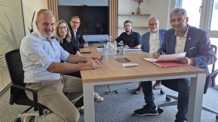Sechs Führungskräfte der Waghubinger Firmengruppe sitzen bei einer Besprechung an einem Konferenztisch anlässlich der Neuaufstellung der Unternehmensführung.